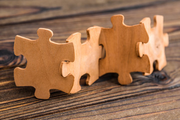 Placing a piece of the puzzle in a row on a textured rustic wooden table. Conceptual work in the...