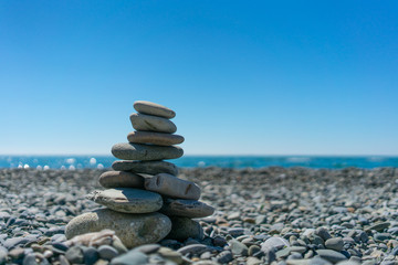 zen-like stones on beach and sun in sky. soft focus on bottom