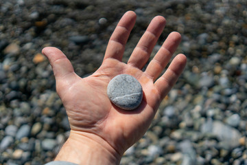 Smooth sea pebbles on the palm - time to collect stones and sum up
