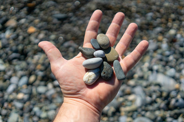 Smooth sea pebbles on the palm - time to collect stones and sum up