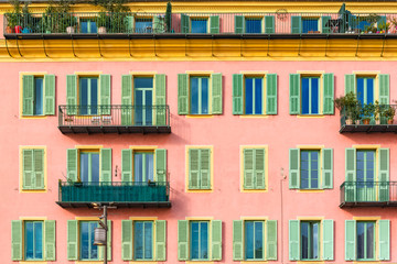 Fototapeta na wymiar Nice, France, colorful pink facade, with typical windows, balconies and shutters 