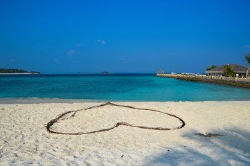 Romantic Heart on sand of a tropical beach. Clear turquoise ocean. Maldives islands.
