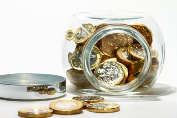 Glass jar full of pound coins isolated on a white background
