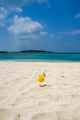 fruity cocktail on a sandy beach with blue water - maldives
