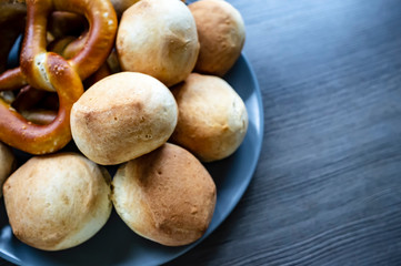 Appetizing, baked, soft buns and pretzels lie in a plate, on a wooden textured table. Traditional food. Oktoberfest.
