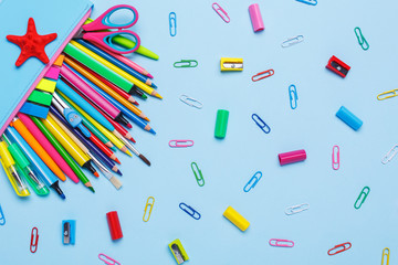 Colored pens, pencils, markers and other objects lie on a light blue background.