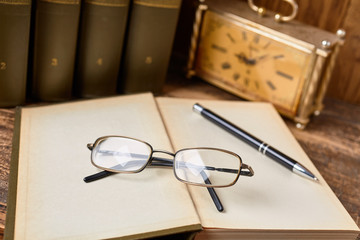 Fototapeta premium Open book with eyeglasses and a pen for notes