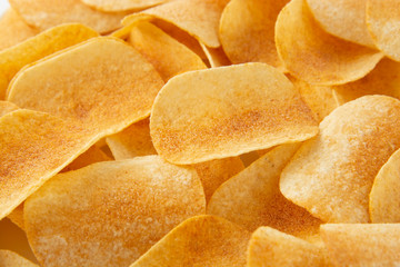 Background golden potato chips texture. Crispy unhealthy snack isolated.