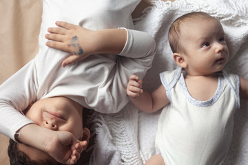 Two brothers lying and posing. Portrait of brothers. Two months baby boy and five years small boy playing cheerfully. View from above. Emotional expressions of children.