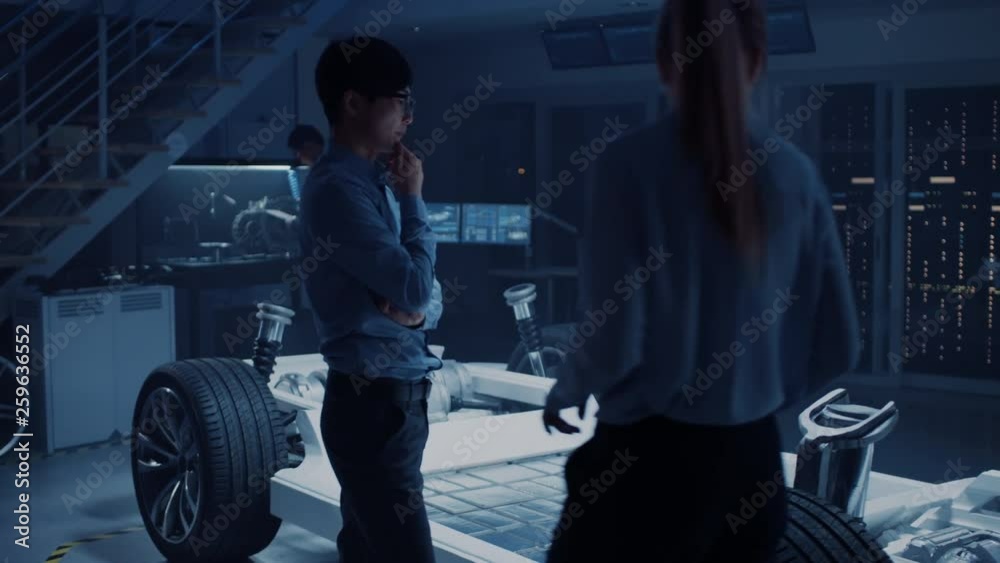 Aufkleber Camera Walkthrough in a Development Laboratory Room with Diverse Professional Team of Engineers and Scientists Working on a Electric Car Chassis with Wheels, Batteries, Engine and Suspension. 