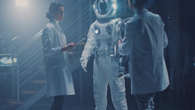 Diverse Team of Aerospace Scientists and Engineers Wearing White Coats have Discussion, Use Computers, Design New Space Suit Adapted for Galaxy Exploration and Travel