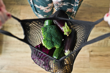 shopping concept. young woman holding textile glocery bag with vegetables. zero waste. plastic free. potatoes, eggplant, squash, broccoli, cabbage