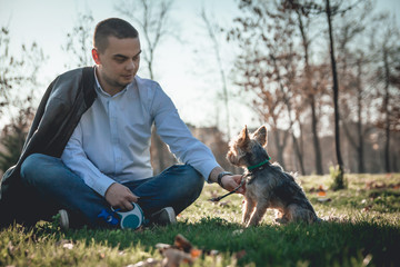 Man and his Yorkshire terrier dog having fun in the park