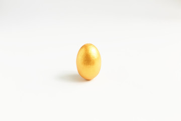 Golden egg, a symbol of making money and successful investment, standing on white background. Minimal Happy Easter concept.