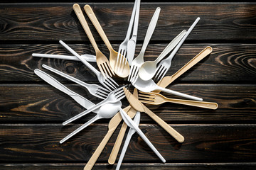 Plastic flatware, forks, spoons, knifes for eco and Earth protection concept on wooden background top view