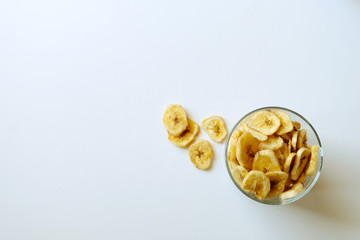 Healthy banana chips on white background. Image with copy space, top view.