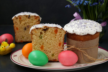 Easter cakes and colorful eggs are located on a plate against a dark background