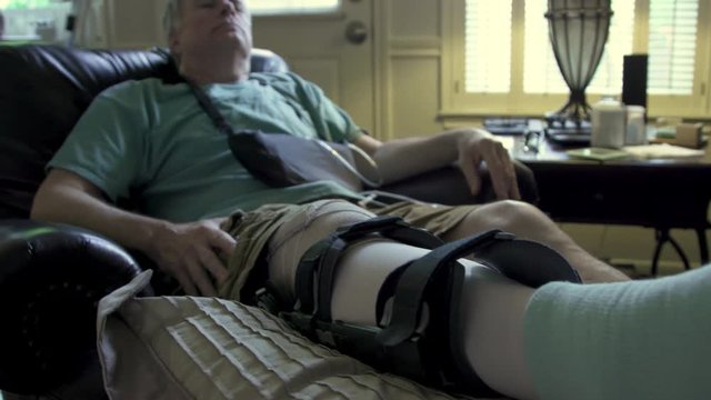 man with a leg brace in an easy chair in pain