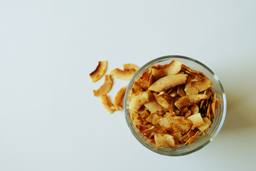 Sliced coconut chips on white background. Image with copy space, top view