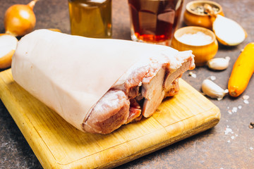 Raw pork knuckle on an cutting board. Rustic style.