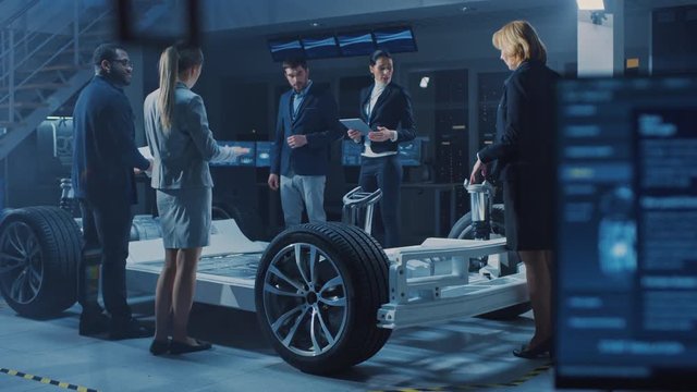 International Team of Automobile Design Engineers Introducing Futuristic Autonomous Electric Car Platform Chassis to a Group of Investors and Businesspeople. Screens Show 3D CAD Software