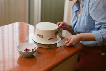 confectioner decorates white cake with color pink cream