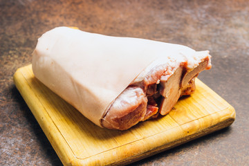 Raw pork knuckle on an cutting board. Rustic style.