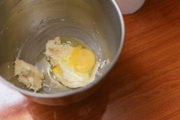 girl breaks an egg in a metal bowl for dough