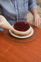 confectioner squeezes the cream on the cake. Girl making a cake
