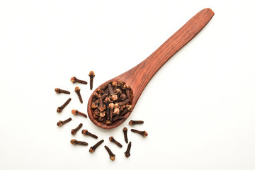 Organic cloves in a wooden spoon over white background