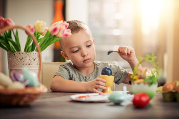 Cute little child painting Easter eggs