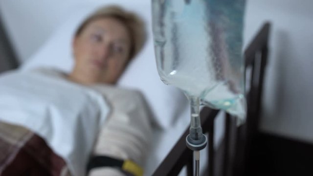 Dropper standing near worried patient awaking after surgery operation, medicine