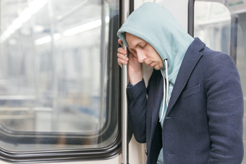 A tired man after work goes home on the subway train. Young exhausted male fell asleep standing up...