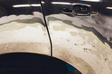 Preparation for painting a car element using emery sender by a service technician leveling out...