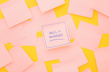 Hello Monday; text on sticky note on pink table. Top view.