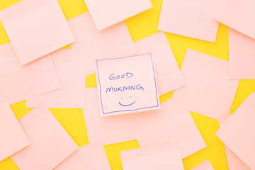 Good morning; text on sticky note on pink table. Top view.
