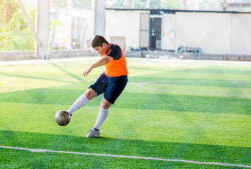 The Asian kid soccer player shoot bounce ball at  to goal on artificial turf to goal