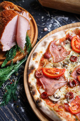 Spicy pizza with hunting sausages, ham and mushrooms