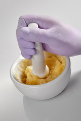 Closeup of the hands of a pharmacist or scientist, holding a mortar and pestle and wearing rubber gloves,pharmacist mixing medicine