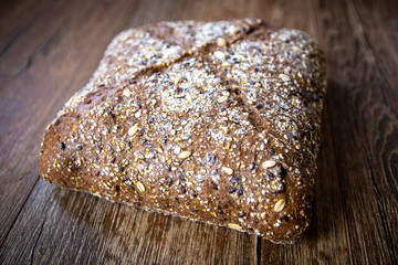 Homemade healthy freshly baked organic whole grain bread with healthy seeds on wooden table