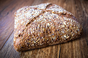 Homemade healthy freshly baked organic whole grain bread with healthy seeds on wooden table