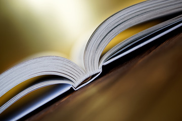 Opened book is lying on the boards on a golden background. Close-up
