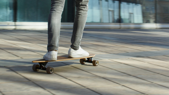Male skateboarder riding and practicing longboard in the city, outdoors, in motion, cropped image. Man down the street with skateboard. Leisure, healthy lifestyle, extreme sports concept