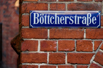 blue street sign with white letters on a red brick wall in the old city of Bremen (Germany) - "Böttcherstraße" is the name of the street