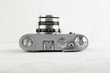 The old 35 mm film rangefinder camera on white cement background.