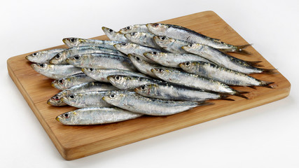 Fresh raw sardines on wooden cutting board