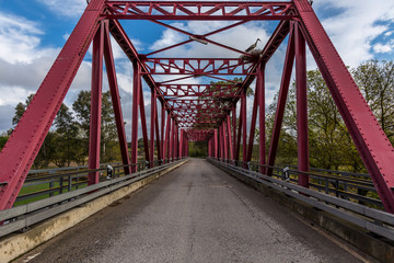 Metallic Red Bridge Over a River Under a Blue Sky
