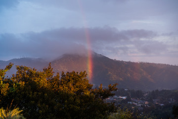 Brilliant rainbow over California mountains with clouds at sunset