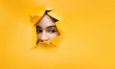 Surprised teenage funny girl face. Cute attractive girl looking through hole. Copy space for...