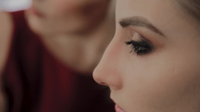 Makeup artist applies professional makeup to a beautiful young girl. New concept in makeup.